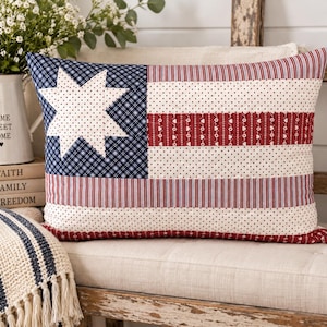 May include: A rectangular throw pillow featuring a patchwork design with a blue and white plaid canton containing a white eight-pointed star. The field consists of alternating horizontal stripes of red and white polka dots and red and white pinstripes.