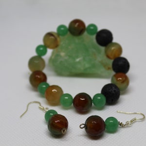 May include: A green, brown, and black beaded bracelet and matching earrings. The bracelet is made with agate and lava rock beads. The earrings are made with agate beads.