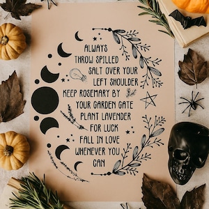 May include: A beige print with black text and illustrations, including moons, stars, and botanical elements. The text reads, "Always throw spilled salt over your left shoulder..." Decorative pumpkins, leaves, and a skull surround the print, creating a Halloween theme.