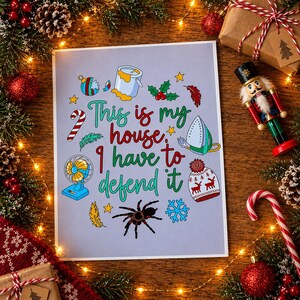 Könnte beinhalten: Ein rechteckiger Druck auf hellviolettem Hintergrund mit dem Text "This is my house, I have to defend it" in Rot und Grün. Um den Text herum befinden sich Illustrationen eines Farbeimers, Bügeleisens, Ventilators, einer Spinne, Mütze, Zuckerstange und Stechpalme.