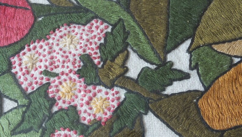 May include: Close-up of embroidered fabric with pink, white and yellow flowers, green leaves and brown branches.