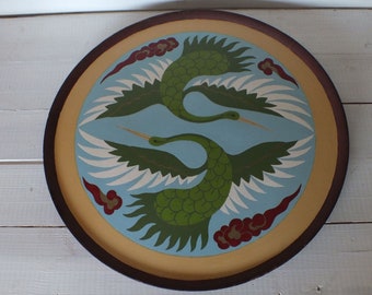May include: Circular wooden tray with a painted design of two green cranes in flight, set against a light blue backdrop. The tray has a brown rim, a gold inner border, and red cloud details.