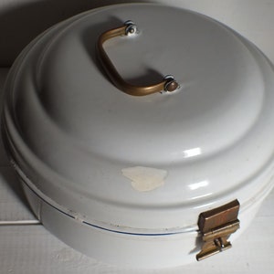 Pode incluir: Pão de esmalte branco com tampa arredondada e alça de latão. A caixa tem um fecho articulado e uma linha de destaque azul. Uma pequena área da tinta está faltando. É um item de armazenamento de cozinha vintage.