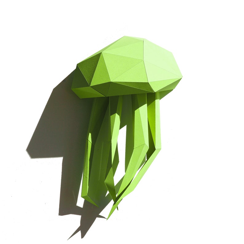 May include: A green papercraft jellyfish with a geometric design. The jellyfish has a dome-shaped head and long, flowing tentacles.