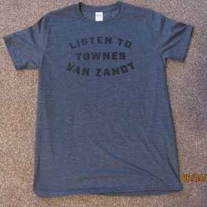 May include: A dark heather grey t-shirt with the text "LISTEN TO TOWNES VAN ZANDT" printed in black.