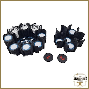 May include: A set of black and white game pieces with blue and white details. The set includes two circular tokens with red numbers, and two black holders with circular slots. The Artificers Forge logo is visible.