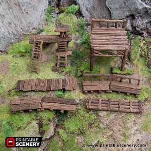 May include: Miniature wooden structures, including a watchtower, a raised platform, ladders, and fence sections. The pieces are made of weathered brown wood, designed for tabletop gaming or model scenery. The scene is set on green moss.