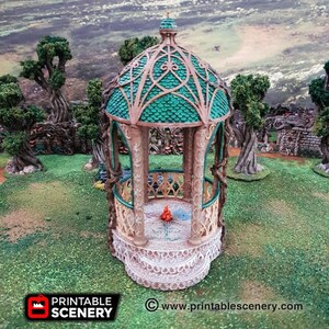 Może przedstawiać: Miniaturowy pawilon wydrukowany w 3D z zielonym dachem i skomplikowanymi detalami. Pawilon jest wykonany z beżowego plastiku i ma małe ognisko w środku. Pawilon jest otoczony zielonym terenem trawiastym.