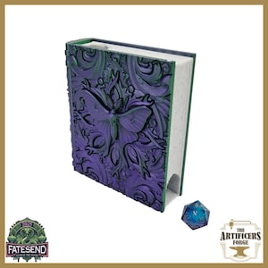 May include: A purple fantasy book with a butterfly and floral design, green edges, and a blue and teal die. The book's cover features intricate embossed details. The book is a prop for role-playing games.