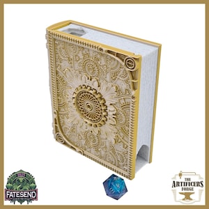 May include: A gold-colored, intricately designed book-shaped box with a detailed floral and gear pattern on the cover. A blue and purple 20-sided die sits in front of the box. The box has a slot on the top and a curved opening on the side.