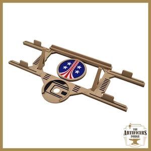 May include: A tan-colored, laser-cut wooden model kit with a circular emblem featuring a red and white design with blue stars. The kit has a complex, geometric design with multiple interlocking pieces. The logo for "The Artificers Forge" is in the bottom right corner.