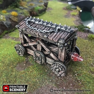 May include: A wooden siege tower with a chain and spikes on top, on wheels, with a red ram at the front. The tower is made of brown wood and has a weathered look.