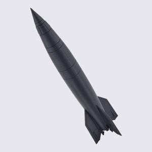 May include: A black and gray model of a rocket with a pointed nose cone and fins at the back.