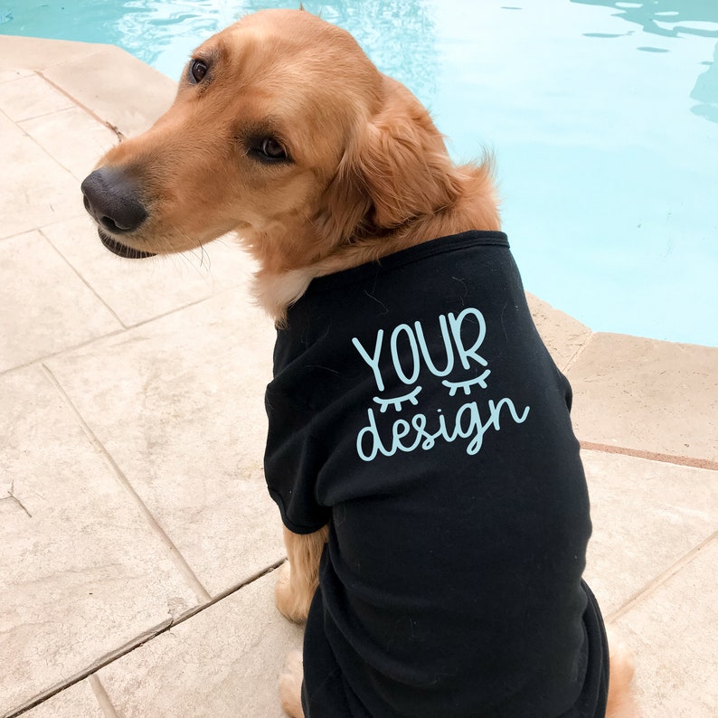 May include: A golden retriever dog wearing a black t-shirt with the text "YOUR design" in light blue.