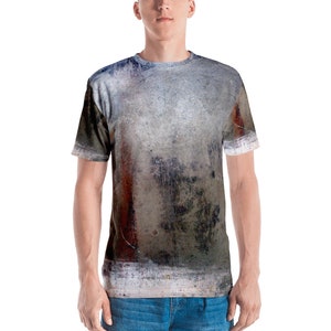 Könnte beinhalten: Ein graues, weißes und braunes T-Shirt mit einem abgenutzten, abstrakten Muster. Das Shirt hat einen Rundhalsausschnitt und kurze Ärmel.