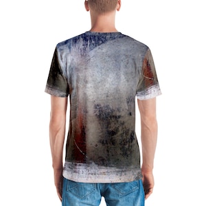 Puede incluir: Una camiseta gris, azul y &oacute;xido con un dise&ntilde;o abstracto. La camiseta tiene cuello redondo y mangas cortas.
