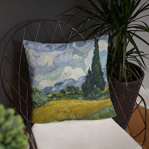 May include: A throw pillow featuring a painting of a landscape with a field of yellow wheat, a row of cypress trees, and a blue sky with white clouds. The painting is in the style of Vincent van Gogh.