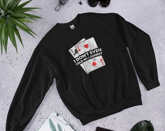May include: Black sweatshirt with a white graphic of two playing cards and the text "I don't even fold my laundry".