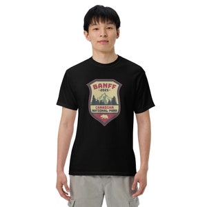May include: Black t-shirt with a vintage-style graphic of a mountain range and a bear. The graphic says "Banff *2023* Canadian National Park".