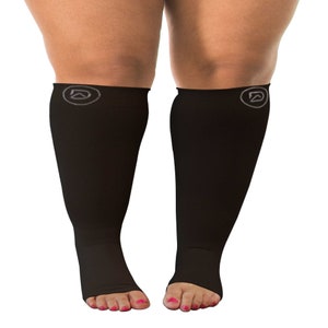 May include: A pair of black compression socks with open toes. The socks have a logo on the calf.