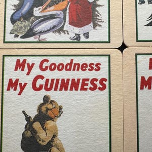 Puede incluir: Posavasos cuadrados con borde crema y ribete verde. Los posavasos presentan ilustraciones de animales y Pap&aacute; Noel. Un posavasos tiene el texto "My Goodness My Guinness" en letras rojas.