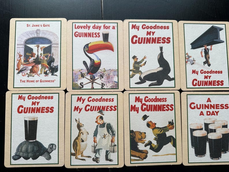 Puede incluir: Un conjunto de tarjetas publicitarias vintage de Guinness. Cada tarjeta presenta ilustraciones coloridas y texto, incluyendo frases como "My Goodness My Guinness" y "A Guinness a Day". Las tarjetas muestran varias escenas caprichosas.