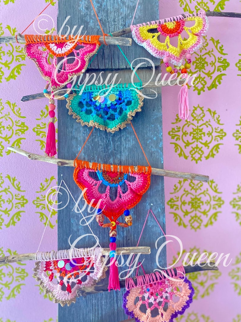Pode incluir: Cinco tape&ccedil;arias de parede de croch&ecirc; em v&aacute;rias cores, incluindo rosa, laranja, amarelo, azul e verde, s&atilde;o exibidas em um fundo de madeira. Cada tape&ccedil;aria apresenta um design circular com contas e borlas.