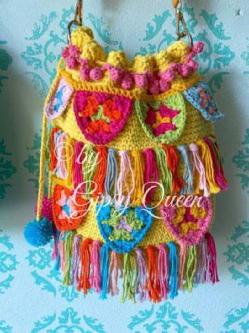 May include: A yellow crocheted bag with colorful tassels and a variety of crocheted flowers. The bag has a long strap and is decorated with pom-poms.