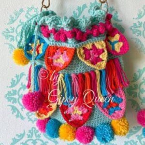 May include: A crocheted turquoise bag with colorful pom-poms and fringe. The bag has a variety of colorful crocheted designs and the text "by Gipsy Queen" is visible.
