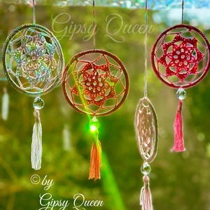 May include: Four handmade dream catchers in various colors hang from a string. The dream catchers have intricate woven designs, tassels, and crystal accents. The text "by Gipsy Queen" is visible.