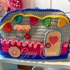 May include: A handmade crochet camper with a gray body, blue trim, and colorful accents. Features a door with a heart, a window, and decorative bunting. The text "Gipsy Queen" is visible.