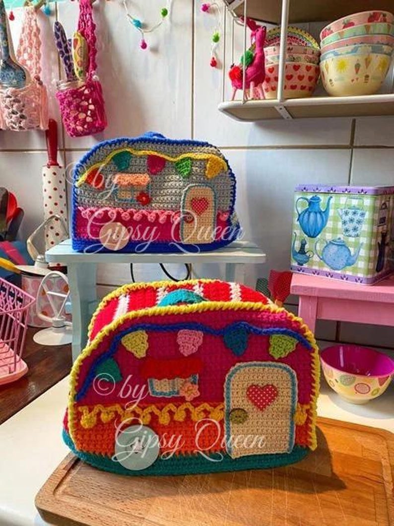 May include: Handmade crochet camper with a red, pink, and blue color scheme. The camper features a door with a heart, a window, and decorative bunting. The text "by Gipsy Queen" is visible on the camper.
