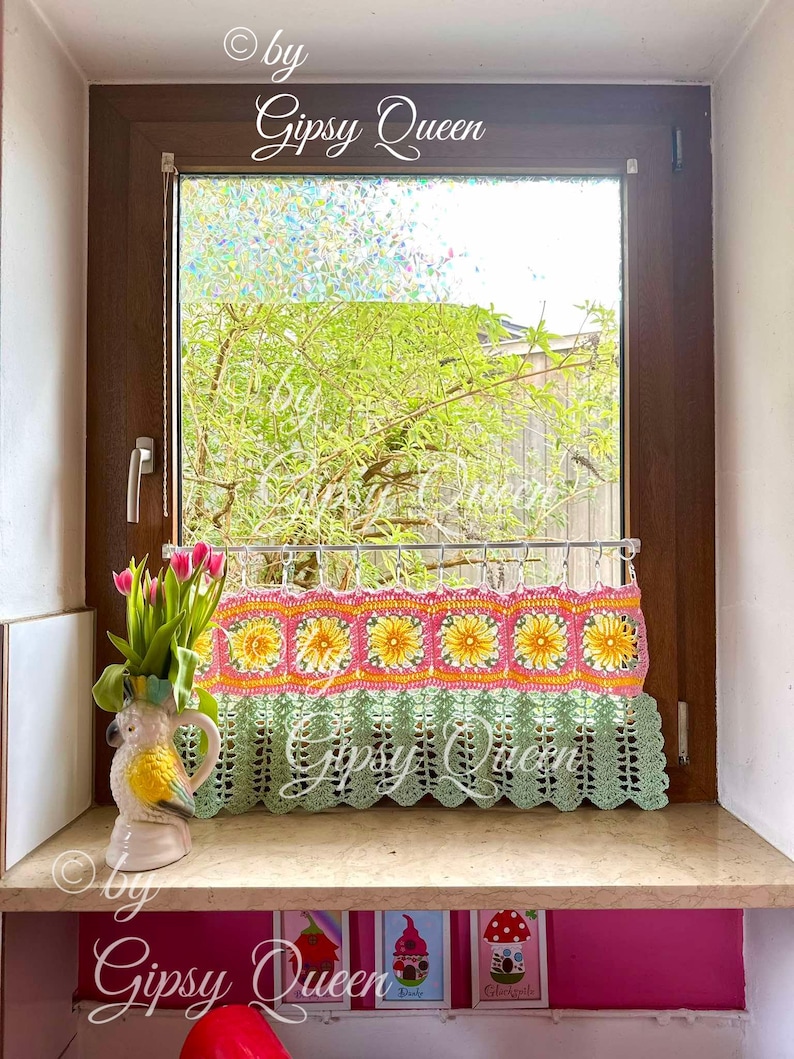 May include: A green crocheted window valance with a pink and yellow floral design. The valance is hanging in a window with a view of green trees. The text "&copy; by Gipsy Queen" is visible in the image.