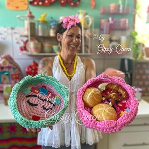 May include: Two crocheted baskets, one pink and one green, with a smiling face design. The pink basket contains bread rolls and a pretzel. The text "© by Gipsy Queen" is visible in the background.