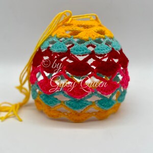 May include: A crocheted bag with a yellow, turquoise, pink, and red pattern. The bag has a drawstring closure and is made with a delicate, open-weave design.