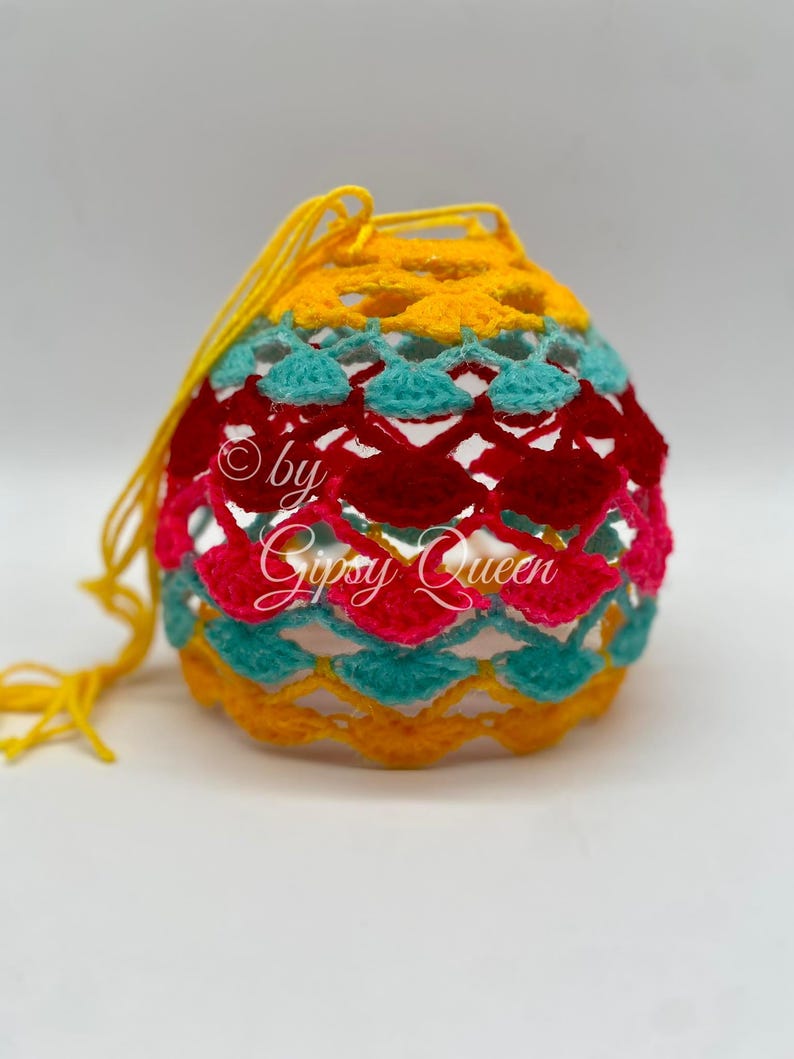 May include: A crocheted bag with a yellow, turquoise, pink, and red pattern. The bag has a drawstring closure and is made with a delicate, open-weave design.