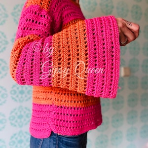 Könnte beinhalten: Ein rosa-oranges Häkeltop mit weitem Glockenärmel. Das Top ist mit einem Lochmuster gearbeitet und hat eine lockere Passform.