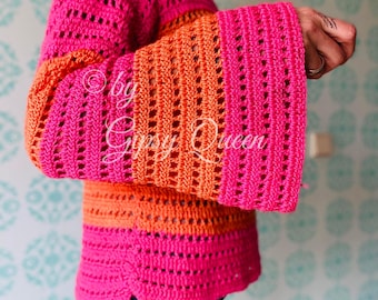 May include: A pink and orange crochet top with a wide bell sleeve. The top is made with a lacy stitch and has a relaxed fit.
