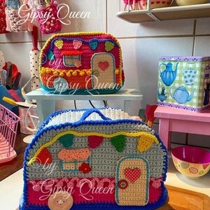 May include: Two colorful crochet camper-shaped bags. The top bag is red, orange, and blue, with a door and heart detail. The bottom bag is gray, blue, and pink, with a door and heart detail. The text "by Gipsy Queen" is visible.
