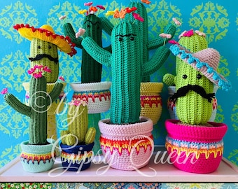 May include: Five crocheted cactus plants in colorful pots with flowers on top. The cacti are wearing sombreros and have mustaches. The pots have a rainbow drip effect. The cacti are sitting on a shelf with a patterned drawer below.