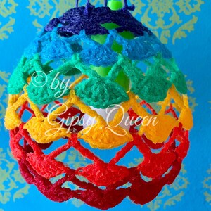 May include: A rainbow crocheted lampshade with a white lightbulb inside. The lampshade is hanging from a ceiling and is made of different colored yarn.