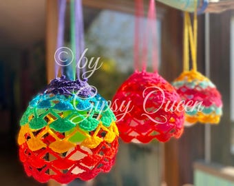 Pode incluir: Três ornamentos pendurados de crochê com cores do arco-íris sobre um fundo branco. Os ornamentos estão pendurados em um galho de madeira flutuante pintado de turquesa com bolinhas brancas. O texto "by Gypsy Queen" é visível na imagem.