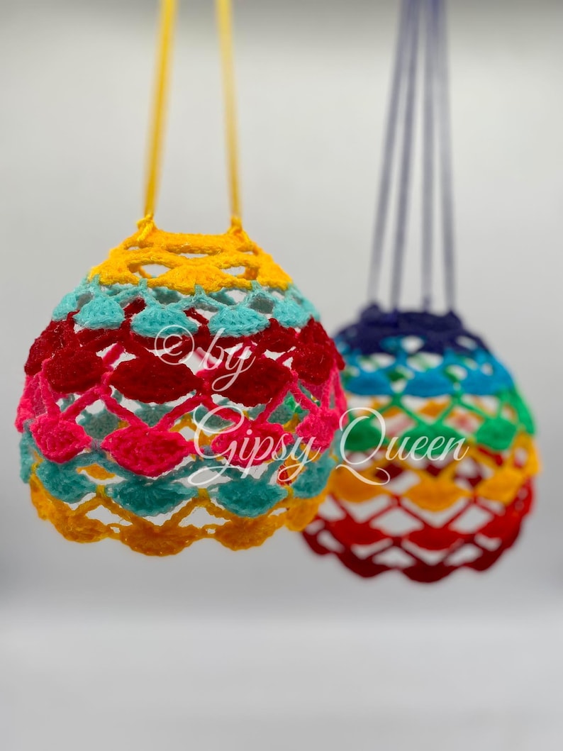 May include: Two crocheted hanging ornaments in rainbow colors. The ornament on the left is yellow, red, pink, blue, and green. The ornament on the right is blue, green, yellow, red, and orange.