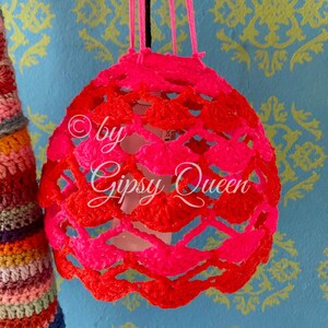 May include: A pink and red crocheted lampshade with the text "by Gipsy Queen" hanging from a string.
