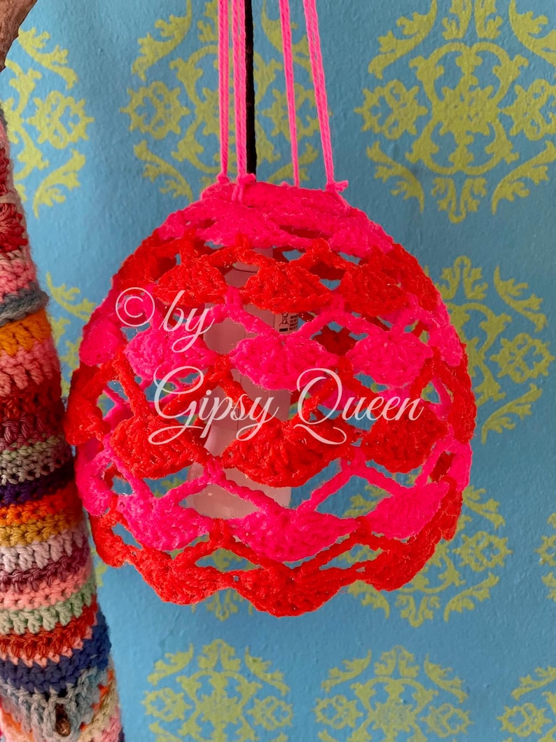 May include: A pink and red crocheted lampshade with the text "by Gipsy Queen" hanging from a string.