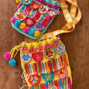 May include: Two crocheted bags with colorful tassels and pom-poms. The bags are yellow and turquoise with floral patterns. The bags have a yellow strap with white flowers.