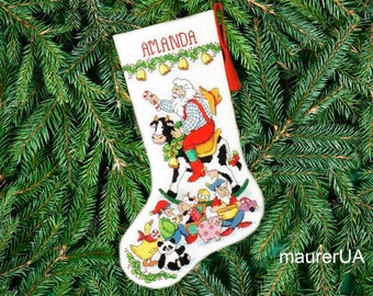 Könnte beinhalten: Ein weißer Weihnachtssocken mit rotem Besatz und dem personalisierten Namen "ALANDA". Der Socken zeigt einen Weihnachtsmann, der auf einem Kuh reitet, mit einer Gruppe von Elfen und Tieren um ihn herum.