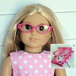 May include: Pink oval-shaped glasses with clear lenses for a doll. The glasses are shown on a doll with blonde hair and a pink and white polka dot dress. The glasses are also shown in a close-up with a pink and floral patterned case.
