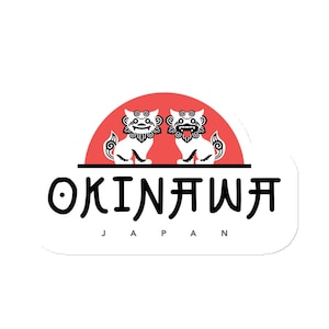 May include: A white sticker with a red sun and two white stylized lion-like creatures. The text "OKINAWA JAPAN" is below the sun.