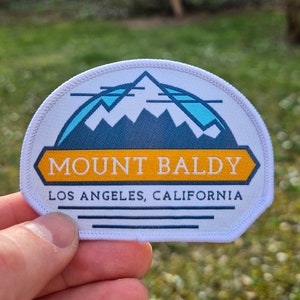 May include: White patch with a blue mountain range graphic and the text "Mount Baldy Los Angeles, California".